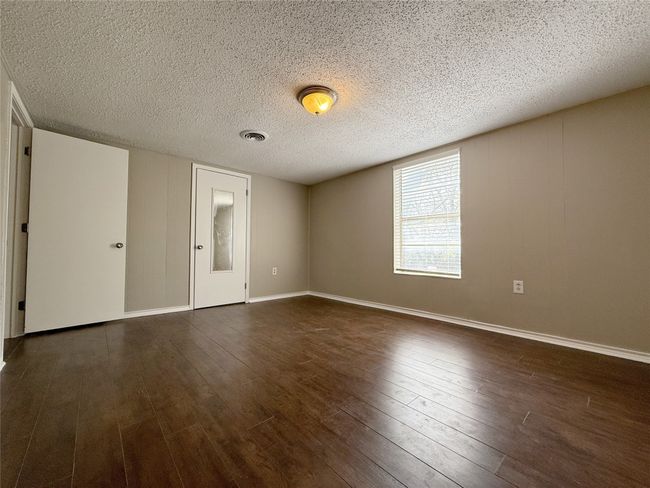 Unfurnished room with dark wood finished floors, a textured ceiling, baseboards, and visible vents | Image 13