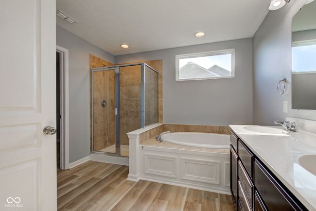 full bathroom featuring a bath, a shower stall, double vanity, wood finished floors, and recessed lighting | Image 34