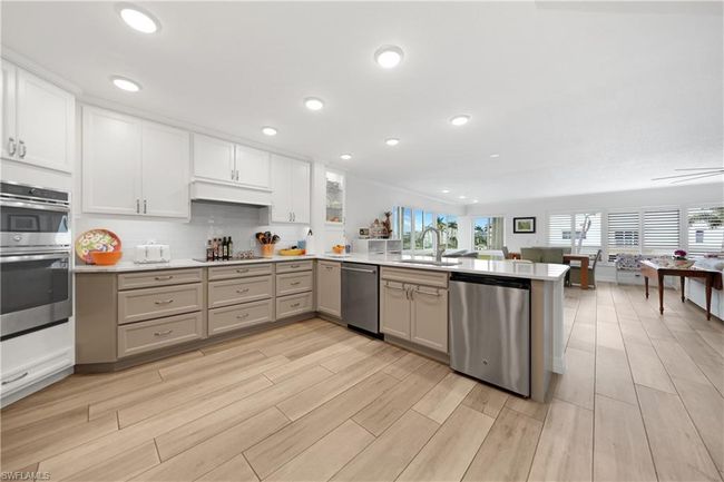 Kitchen featuring sink, backsplash, kitchen peninsula, white cabinets, and appliances with stainless steel finishes | Image 8