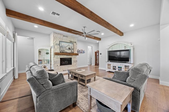 Striking wood beams, combined with the elegant stone fireplace, bring a sense of warmth and sophistication to the room. | Image 13