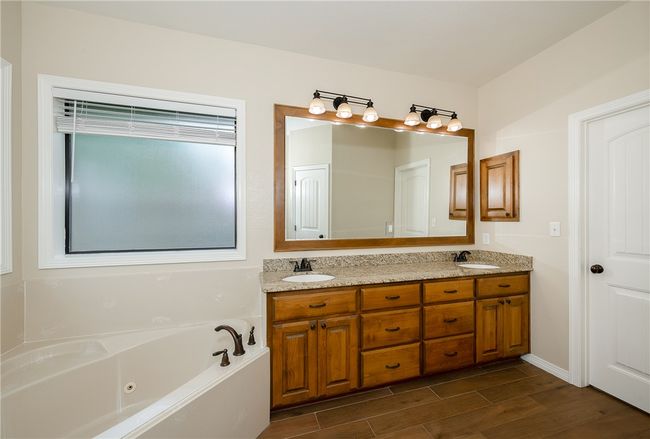 Full bathroom featuring a tub with jets, wood finished floors, double vanity, and a sink | Image 17