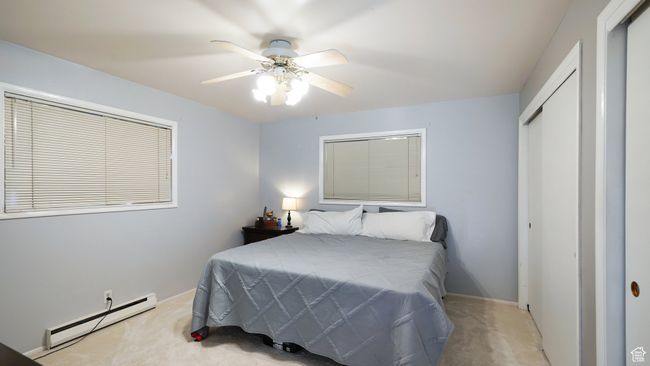 Carpeted bedroom featuring a baseboard radiator, a closet, baseboards, and a ceiling fan | Image 12