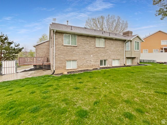 Back of house with a chimney, a wooden deck, a patio area, and a yard | Image 8