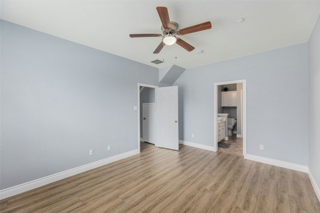 Unfurnished bedroom with light wood-style floors, ensuite bath, and a ceiling fan | Image 14