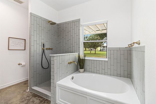 Full bathroom with visible vents, a walk in shower, a bath, and concrete floors | Image 16