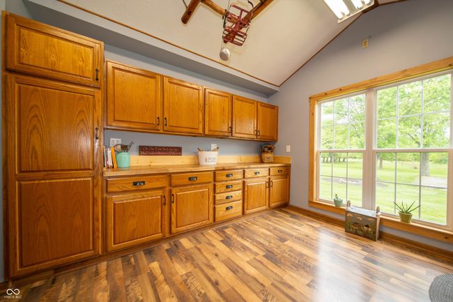 kitchen with lofted ceiling, brown cabinetry, wood finished floors, plenty of natural light, and light countertops | Image 20
