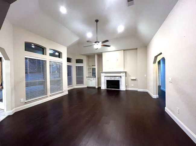 Unfurnished living room with a ceiling fan, wood finished floors, a fireplace, and vaulted ceiling | Image 18