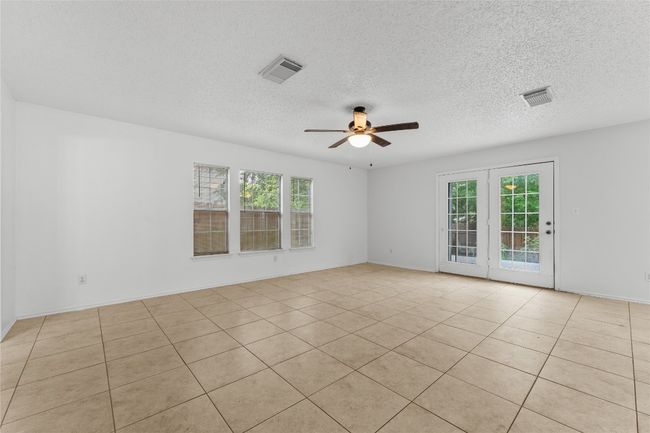 Empty room featuring a ceiling fan, plenty of natural light, a textured ceiling, and light tile patterned floors | Image 8