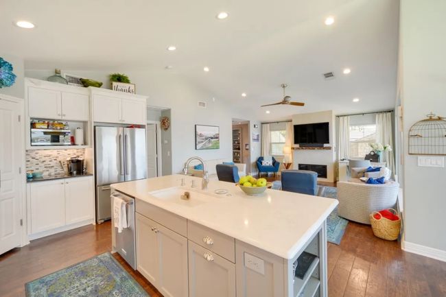 Kitchen featuring appliances with stainless steel finishes, dark wood-style floors, open floor plan, white cabinetry, and lofted ceiling | Image 24