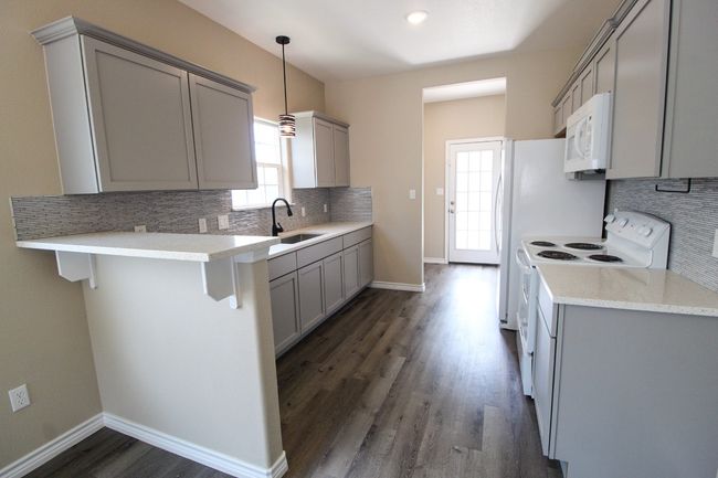 Kitchen with gray cabinetry, white appliances, backsplash, and dark wood-style floors | Image 6