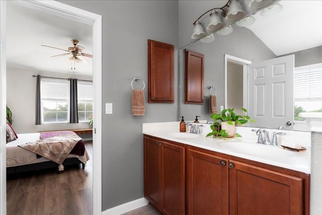 Ensuite bathroom featuring plenty of natural light, double vanity, ceiling fan, baseboards, and lofted ceiling | Image 16