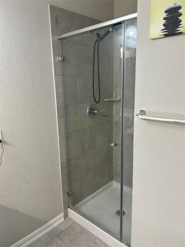 Full bathroom with a stall shower, tile patterned floors, and a textured wall | Image 13