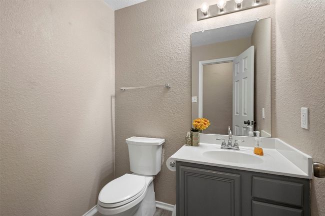 Half bath featuring toilet, vanity, and a textured wall | Image 29