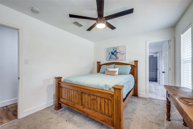 Bedroom featuring baseboards, a ceiling fan, light carpet, and ensuite bath | Image 16