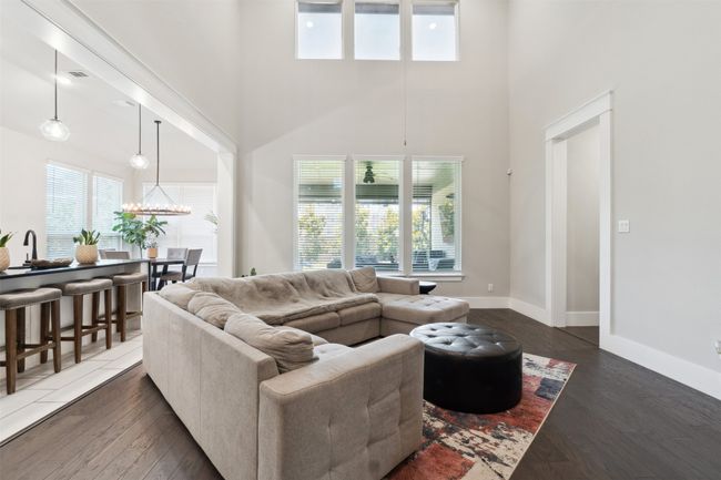 Living area with a towering ceiling, dark wood-type flooring, and a chandelier | Image 8