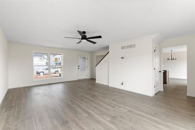 Unfurnished living room with ceiling fan with notable chandelier and light wood-type flooring | Image 3