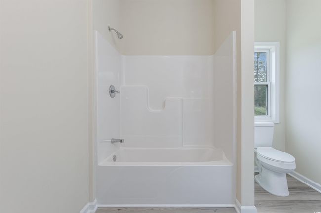 Full bath with baseboards, toilet, wood finished floors, and shower / washtub combination | Image 19