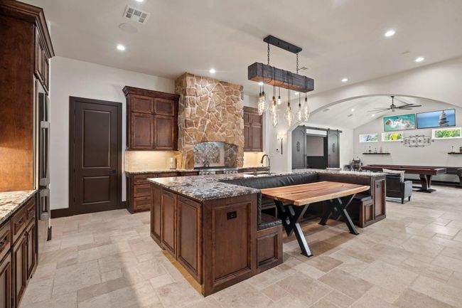 Huge kitchen with walk in pantry at the door in front of you. Large U-shape seating area built into island. Amazing custom light fixture. | Image 15