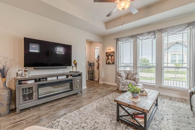 Living room with wood finished floors, ceiling fan, and a tray ceiling | Image 10