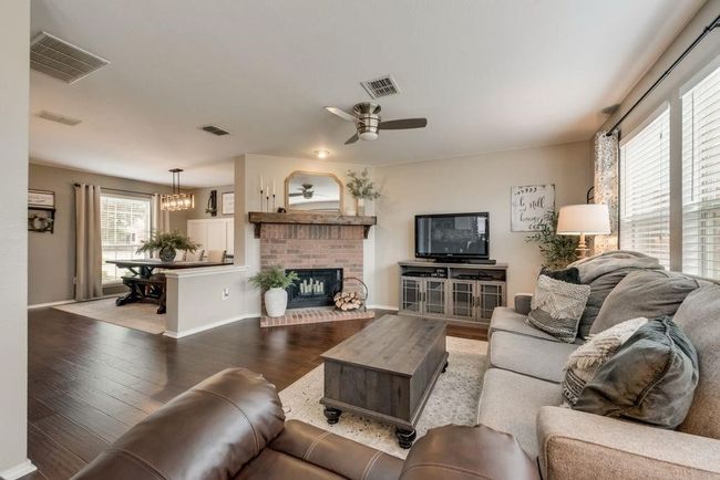 Living room featuring hardwood / wood-style flooring, ceiling fan, a brick fireplace, and a chandelier | Image 7