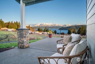 Front porch view (What a Welcome!) from large aggregate patio which extends around the corner to take it all in. Craftsman style details are seen here in the covered area with stone detailing. | Image 2