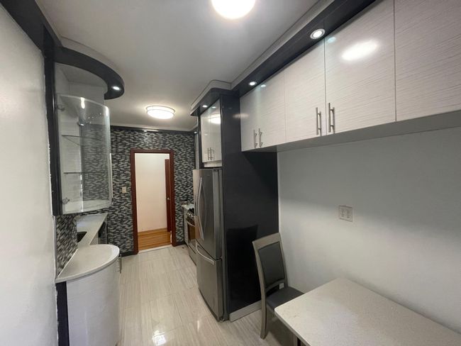 Kitchen with modern cabinets, light countertops, and freestanding refrigerator | Image 6