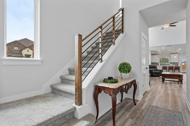 Stairway featuring baseboards, wood finished floors, ceiling fan, and a towering ceiling | Image 5
