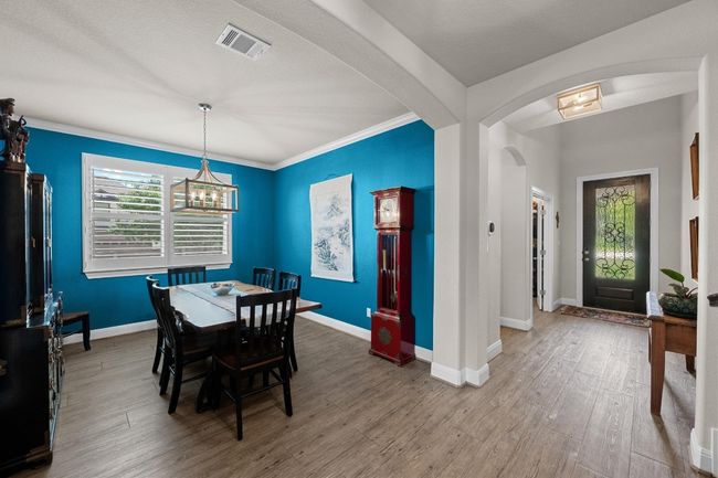 Dining room featuring arched walkways, wood finished floors, a chandelier, and crown molding | Image 16