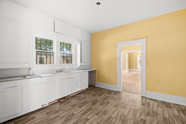 Kitchen featuring light wood finished floors, white cabinetry, and light countertops | Image 4