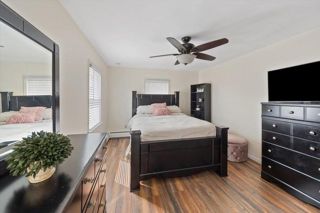Bedroom featuring baseboards, baseboard heating, ceiling fan, and dark wood-type flooring | Image 10