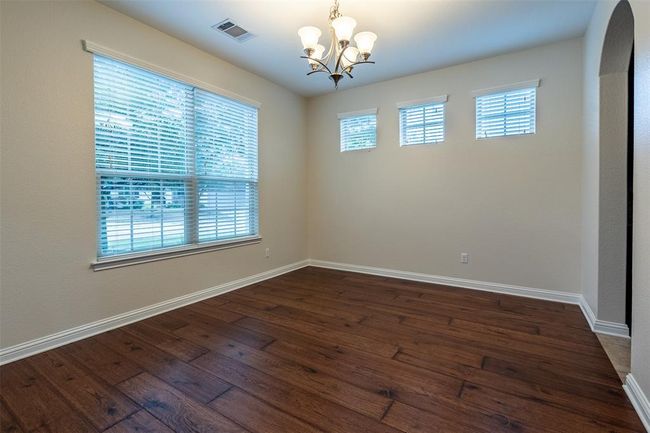 Spare room featuring a chandelier, healthy amount of natural light, dark wood-style flooring, and arched walkways | Image 15