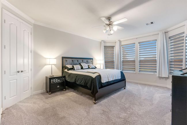 The primary bedroom features a plush carpet, large windows with stylish blinds ample natural light. It has elegant crown molding, all making this room a comfortable and inviting atmosphere. | Image 20