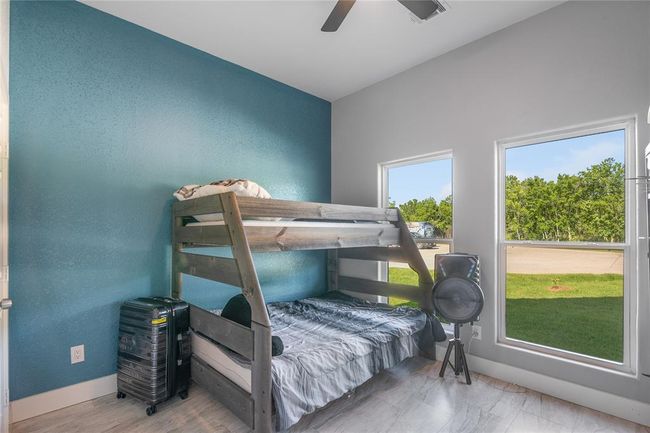 Bright and welcoming secondary bedroom with stylish accent wall and abundant natural light. | Image 14