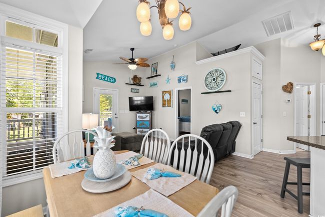 Interior space with white cabinets, visible vents, light wood-style floors, lofted ceiling, and appliances with stainless steel finishes | Image 21