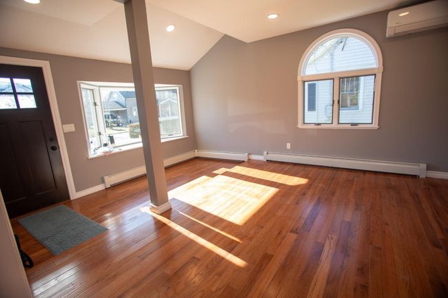Entrance foyer featuring a wall mounted air conditioner, baseboard heating, hardwood / wood-style flooring, and vaulted ceiling | Image 4