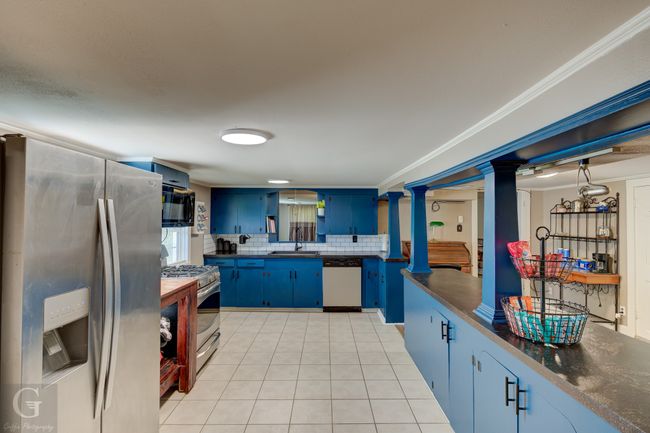 Kitchen with appliances with stainless steel finishes, blue cabinets, a sink, dark countertops, and tasteful backsplash | Image 13