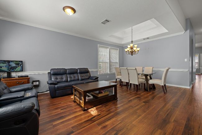 Living room featuring a chandelier, a tray ceiling, wood finished floors, and ornamental molding | Image 5