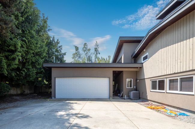View of property exterior featuring an attached garage, concrete driveway, cooling unit, and stucco siding | Image 37