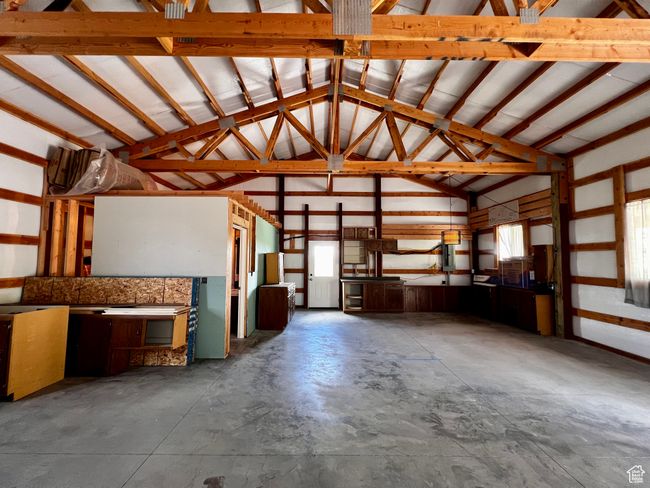 Miscellaneous room with lofted ceiling, unfinished concrete floors, and a garage | Image 25