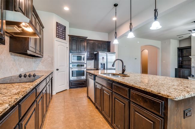 Kitchen with arched walkways, backsplash, appliances with stainless steel finishes, light tile patterned floors, and under cabinet range hood | Image 8