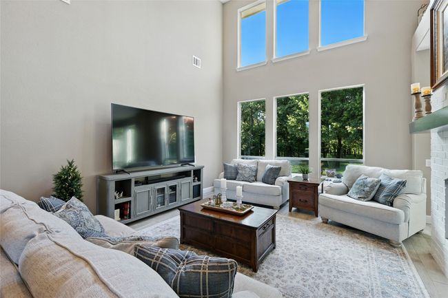 Living area with a towering ceiling, wood like ceramic tile floors, and a see through fireplace | Image 7