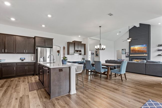 Kitchen with dark brown cabinets, a sink, open floor plan, light wood finished floors, and a fireplace | Image 19