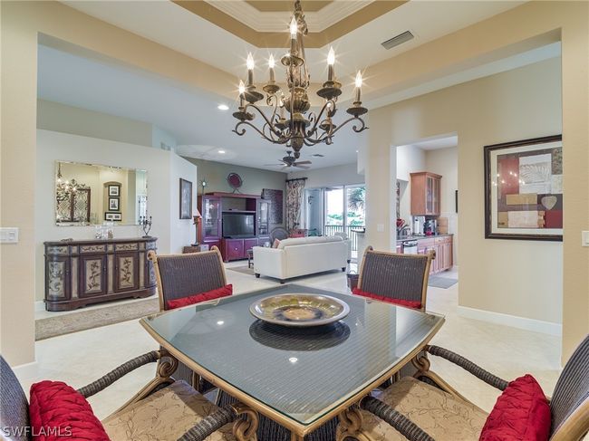 Tiled dining room featuring a notable chandelier, a raised ceiling, and crown molding | Image 13