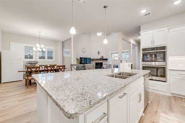Kitchen with a sink, appliances with stainless steel finishes, light wood finished floors, a fireplace, and a center island with sink | Image 10