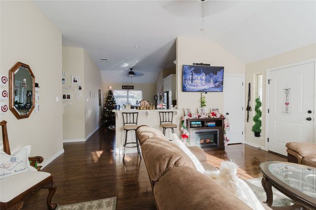 Living room featuring dark hardwood / wood-style floors, ceiling fan, a fireplace, and vaulted ceiling | Image 6