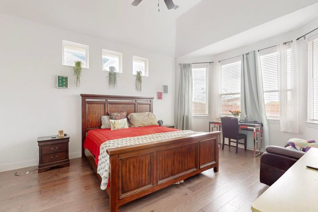 Bedroom with ceiling fan, multiple windows, a high ceiling, and wood finished floors | Image 13