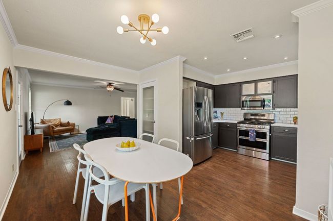 Open kitchen/dining concept with painted cabinetry, updated light fixtures, countertops and SS appliances. | Image 10