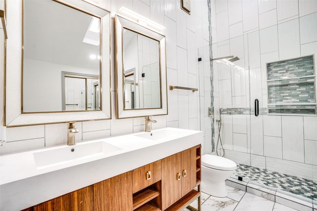 Full bath with a shower stall, toilet, double vanity, marble finish floors, and a skylight | Image 19