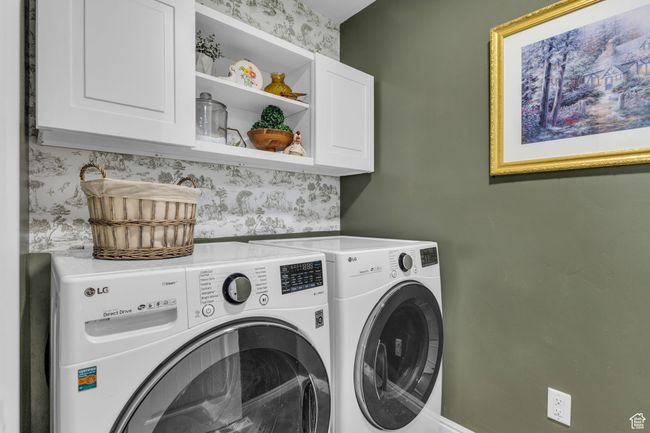 Laundry area featuring washing machine and clothes dryer and cabinet space | Image 14