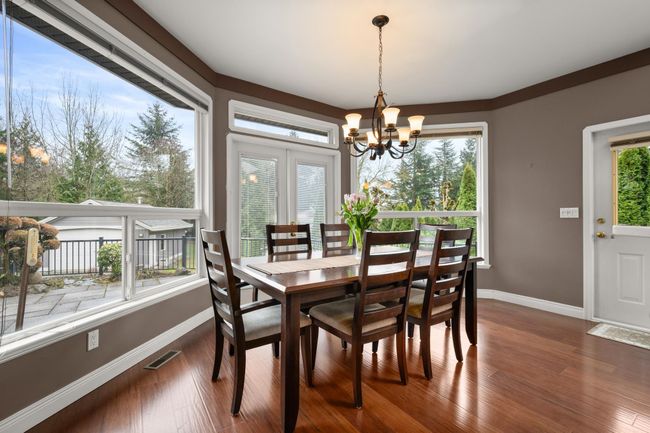 Dining room featuring visible vents, an inviting chandelier, baseboards, and wood finished floors | Image 11